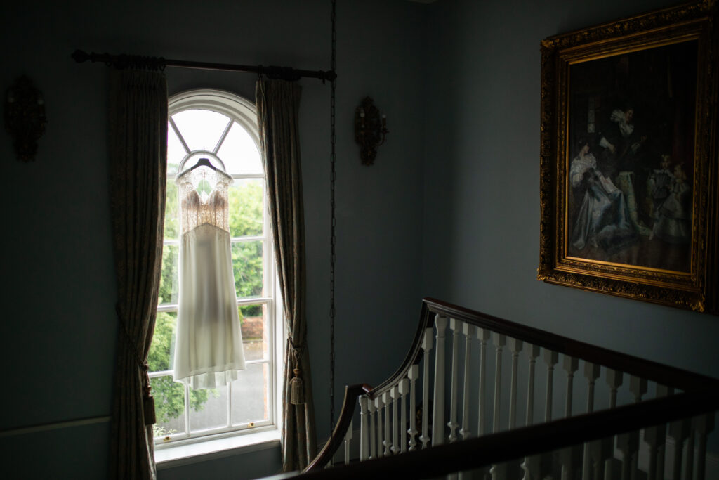 an image of a wedding dress hung in a large window positioned in the middle of a staircase