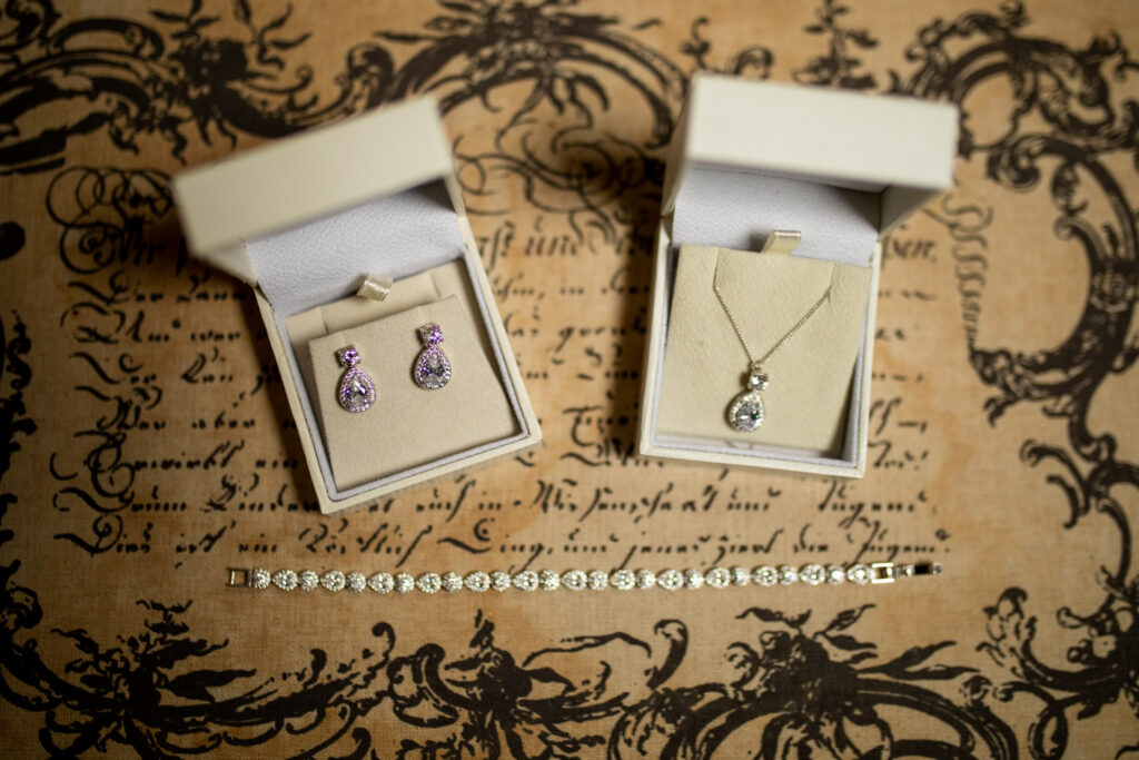 two matching ear rings and a diamond necklace in boxes placed on a table with decorations