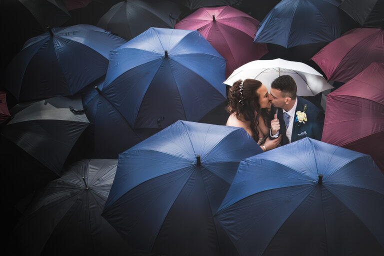 Photograph of a bride and groom under umbrellas at Moxhull Hall