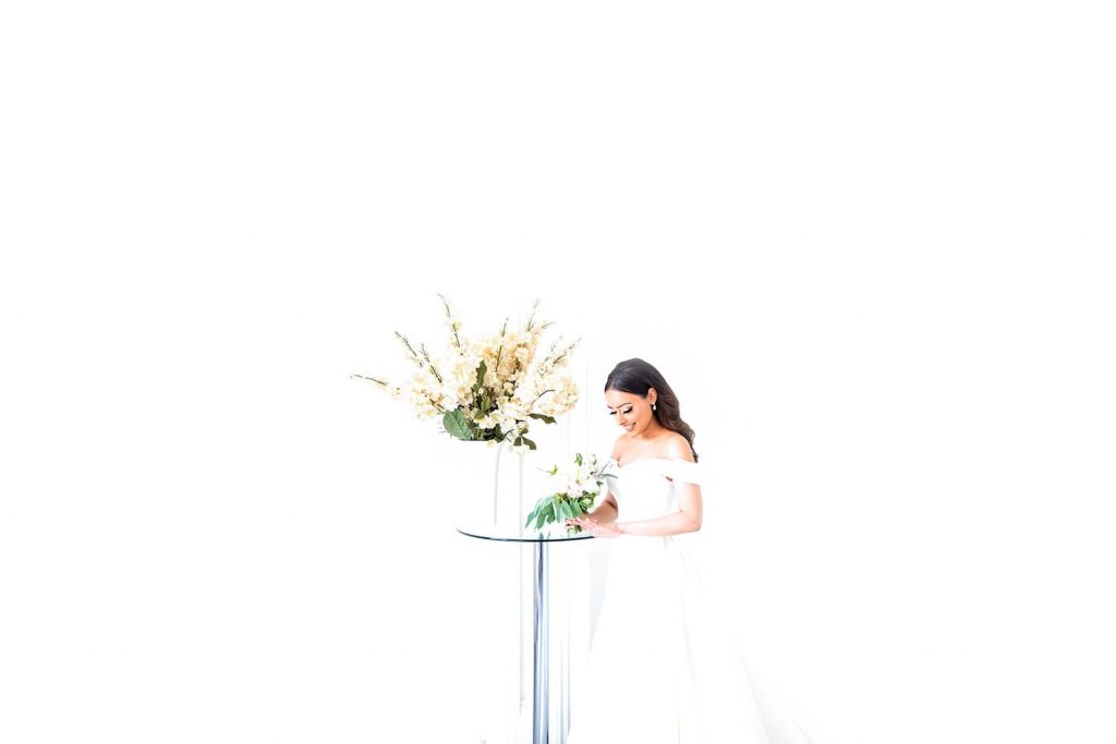beautiful bride with pure white background stood next to table