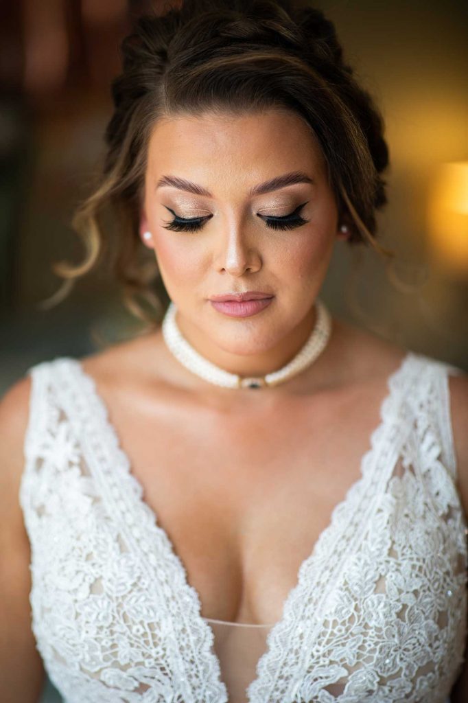 beautiful bride stood in window light in a beautiful wedding dress looking down