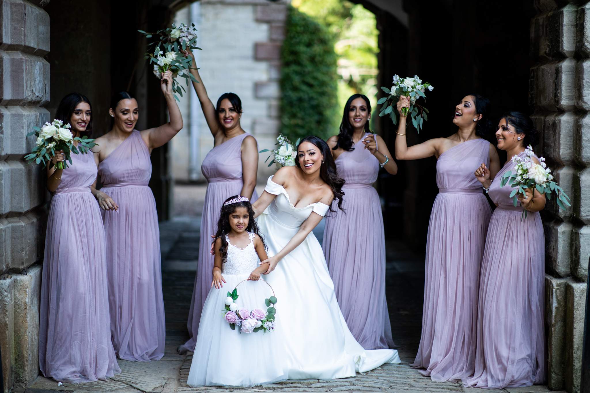 Bride smiling with her bridesmaids standing around her holding up their flowers high in the air.