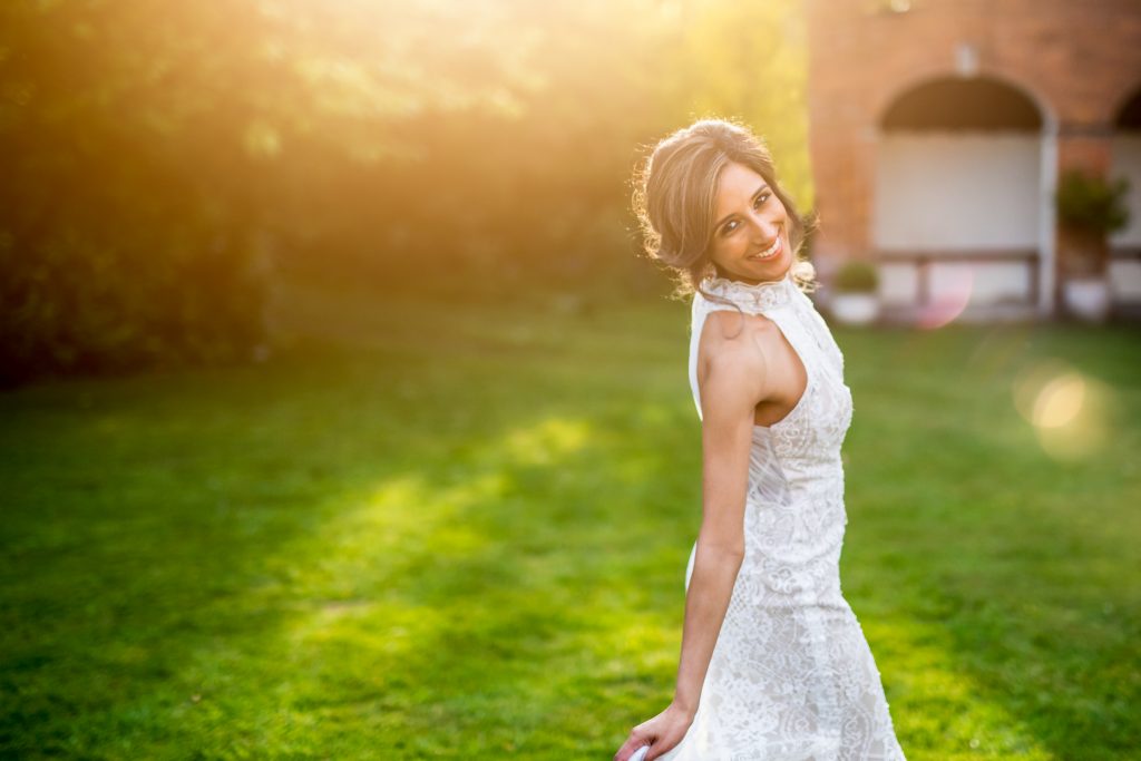 Bride dancing a grass lawn as the sun is setting behind her