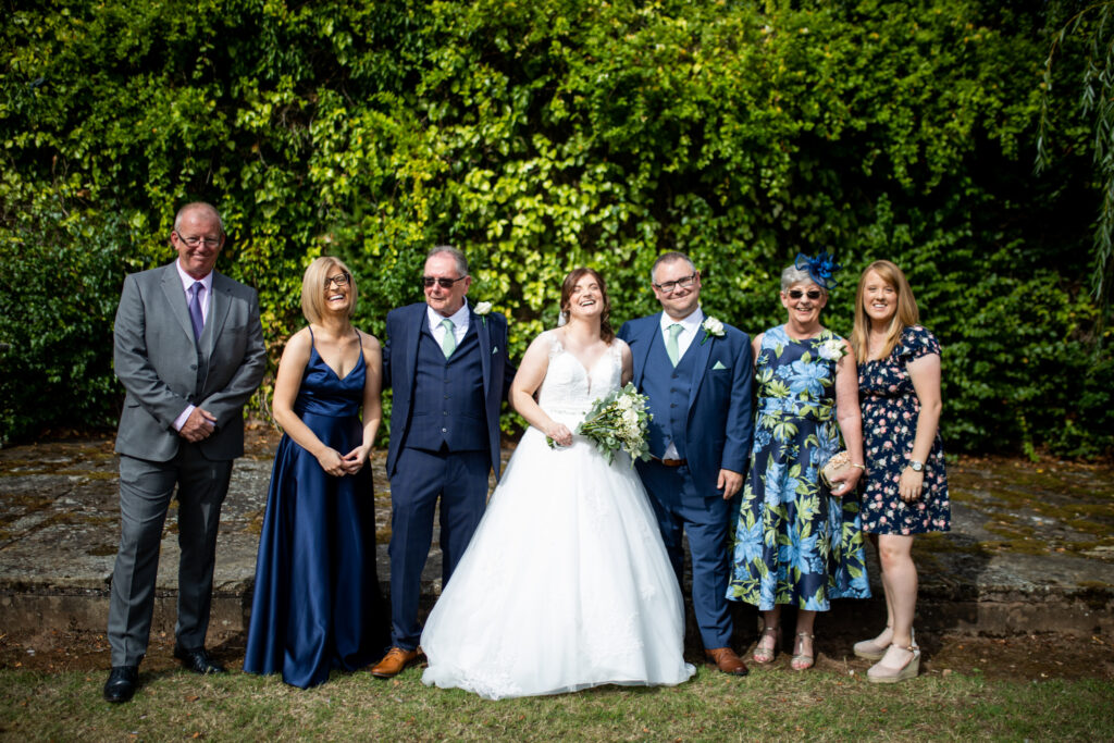 Bride and groom and their family all having a photo together on their wedding day