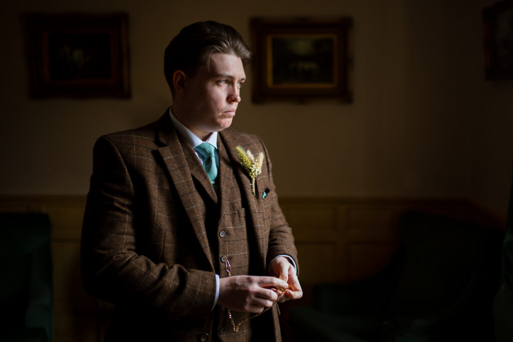Groom looking outside the window just before he is due to get married at the Barns Hotel Cannock