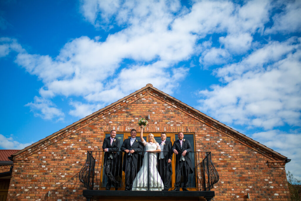 Wootton Park Wedding Photographer. ride and groom standing on the balcony of Wootton Park Wedding venue with their guests.