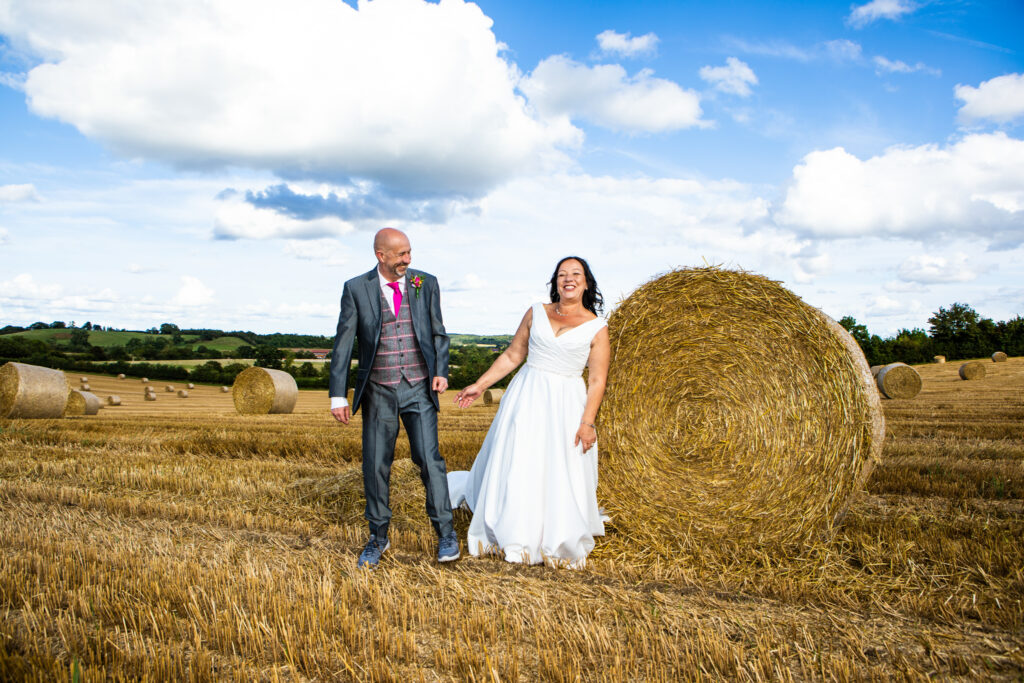 Bride and Groom standing near hay bales on their Wootton Park Wedding adventure!